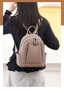 Detail of beige lychee leather backpack showing chevron stitching and side pockets