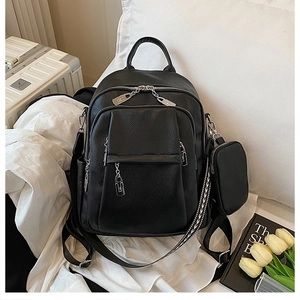 Detailed view of a black pebbled leather backpack with detachable coin purse and woven strap
