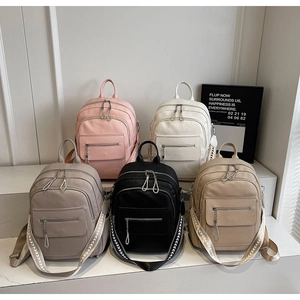 Five colored leather backpacks displayed on tiered marble with patterned fabric straps