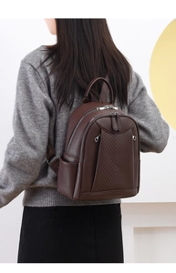 Macro shot of dark brown leather backpack showing litchi grain texture and V-shape stitching