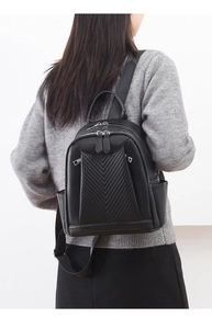 Detail of black faux leather backpack featuring V-shaped stitching and dual zippers