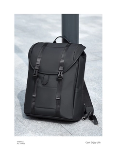 Modern black waterproof travel backpack with dual buckles leaning against a metal pillar