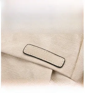 Dettaglio dello zaino in tela beige che mostra la trama saia e la toppa con bordo nero