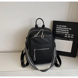 Detail of black pebbled leather backpack with stylish geometric woven shoulder strap