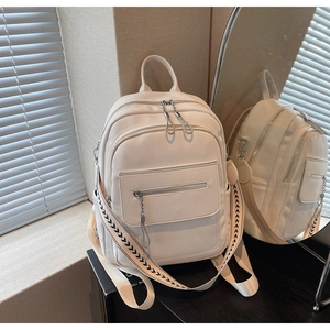 Detail of cream pebbled leather backpack with stylish black and white woven shoulder strap