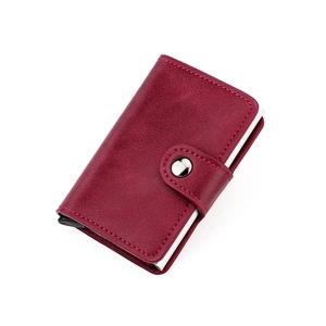 Detail view of wine red leather card wallet with fine stitching and metal snap closure