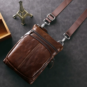 Dettaglio della borsa a tracolla vintage in pelle marrone con cerniere multiple e ganci