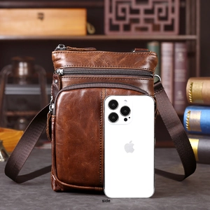 Vista laterale della borsa a tracolla in pelle marrone retrò accanto a uno smartphone per misura