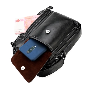 Detail view of black leather shoulder bag with white stitching and interior storage space