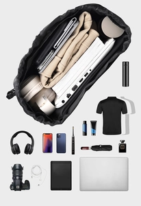 Top-down view of a spacious black drawstring backpack organized with travel essentials