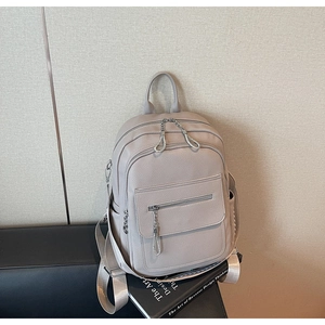 Detail view of beige lychee-patterned leather backpack with dual zipper compartments