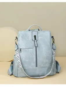 Détail d'un sac à dos bleu clair en similicuir avec bandoulière géométrique et texte Travel Focus