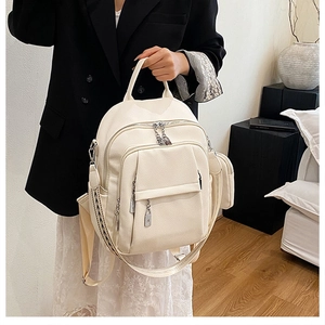 Detail of cream backpack showing lychee texture, woven strap and small side pouch