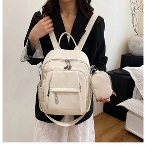 Close-up of off-white pebbled leather backpack with silver hardware and mini pouch