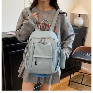 Close-up of sky blue faux leather backpack featuring multiple zip pockets and a wide strap