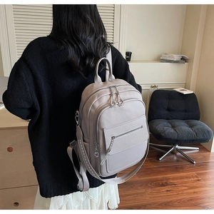 Light purple pebbled leather backpack with silver chains and patterned straps on a model