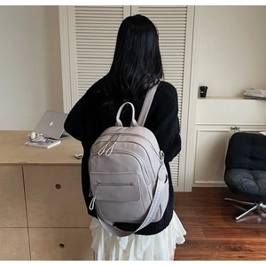 Detail of light purple pebbled leather backpack with multi-layer zippers and side straps