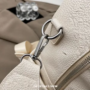 Détail du fermoir mousqueton argenté sur le sac à dos en cuir grainé blanc élégant