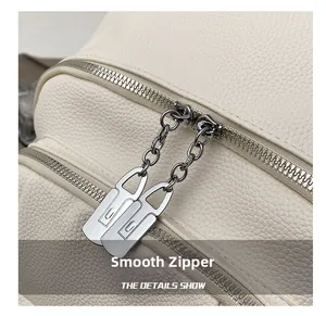 Close-up of dual metal zippers on white lychee pattern leather backpack showing fine detail