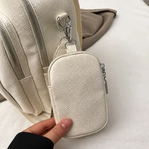 Détail du sac à dos blanc en cuir grainé avec fermetures éclair et pochette amovible