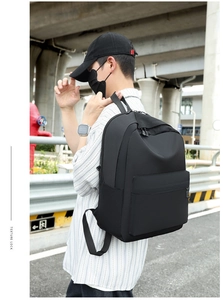 Waterproof black nylon laptop backpack with side pocket shown on male model in city