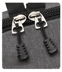 Detail of smooth metal double-zipper with non-slip pull tabs on grey fabric backpack