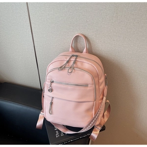 Detail of pink faux leather backpack with litchi texture and silver zipper hardware