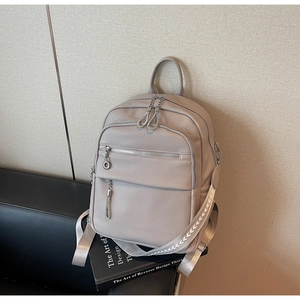 Detail eines grauen Rucksacks aus Kieselleder mit dekorativem gewebtem Schultergurt