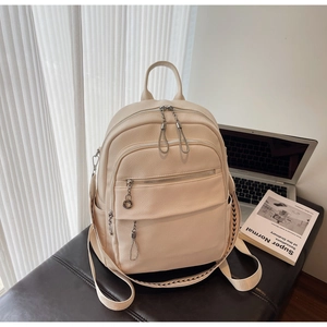 Detail of cream backpack featuring silver zippers and ethnic style woven ribbon trim
