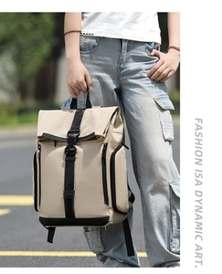 Beige casual backpack with black buckle straps held by hand in urban street setting