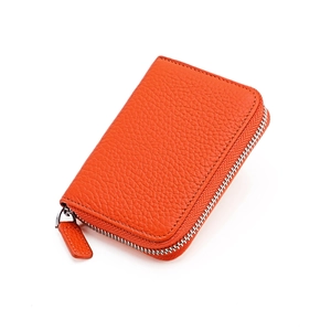 Close-up of orange litchi grain leather card holder with secure metal zipper closure
