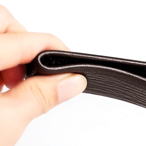 Macro shot of dark brown genuine leather belt texture with flexible lychee grain surface