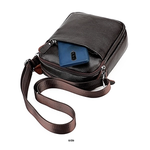 Detail of dark brown leather crossbody bag showing functional front pocket with smartphone
