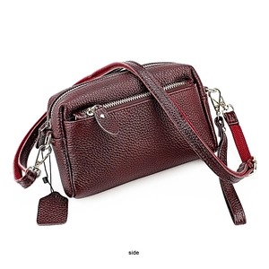 Vue latérale du sac bandoulière en cuir grainé bordeaux avec doubles zips argentés