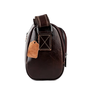 Détail des coutures croisées et de l'anneau métallique sur le sac en cuir marron foncé