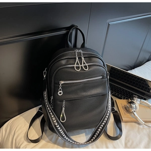 Detail of black pebbled leather backpack with silver zippers and geometric patterned strap