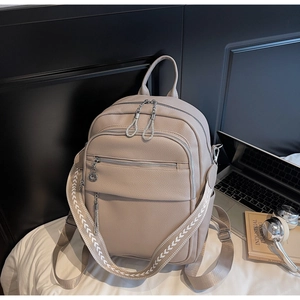 Detailaufnahme des beigen Lederrucksacks mit gewebtem Gurt und mehreren Reißverschlüssen
