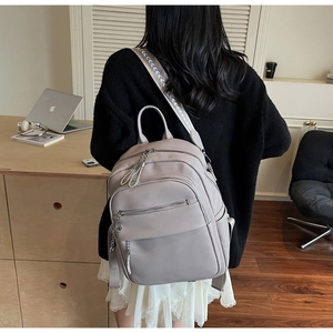 Detail eines Lederrucksacks mit Litschi-Muster, breitem Webriemen und Silberquaste