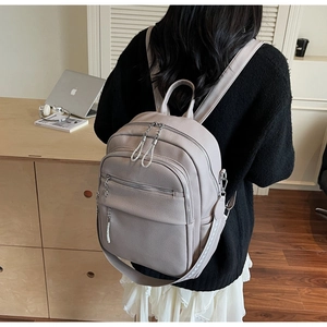 Detailed side view of grey leather backpack with lychee texture and woven wide strap