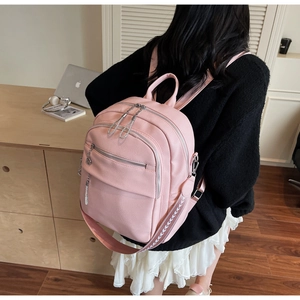 Detail of light pink lychee texture backpack with embroidery and chain accents