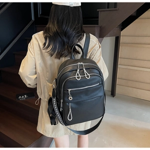 Detail of black pebble leather backpack featuring silver chain and ethnic woven strap