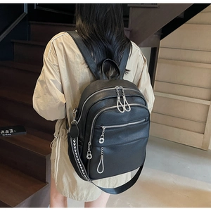 Close-up of black leather backpack with silver chain zippers and multi-zippered pockets