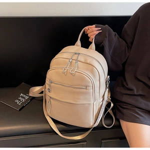 Detail des beigen Lederrucksacks mit mehreren Reißverschlussfächern und Ketten-Anhänger