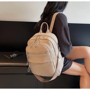 Detail eines beigen Lederrucksacks mit Metallreißverschlüssen und Pfeilmuster-Gurt