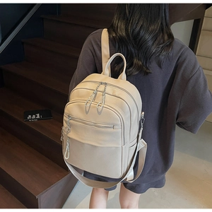 Nahaufnahme eines beigen Lederrucksacks mit Litschi-Textur und großen Staufächern