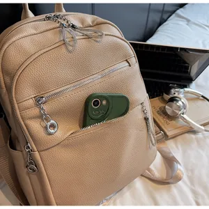 Detail of beige pebble leather backpack with silver zippers next to a laptop