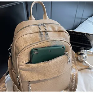 Detail of beige pebbled leather backpack showing multi-zipper pockets and large capacity