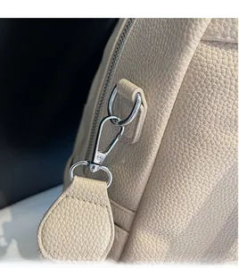Detail of durable silver metal hook on beige pebbled leather backpack with sturdy stitching