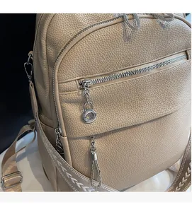 Detail of beige pebble leather backpack featuring silver zipper and chain tassel