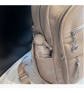 Detail view of the beige leather backpack side pocket holding a matching folding umbrella